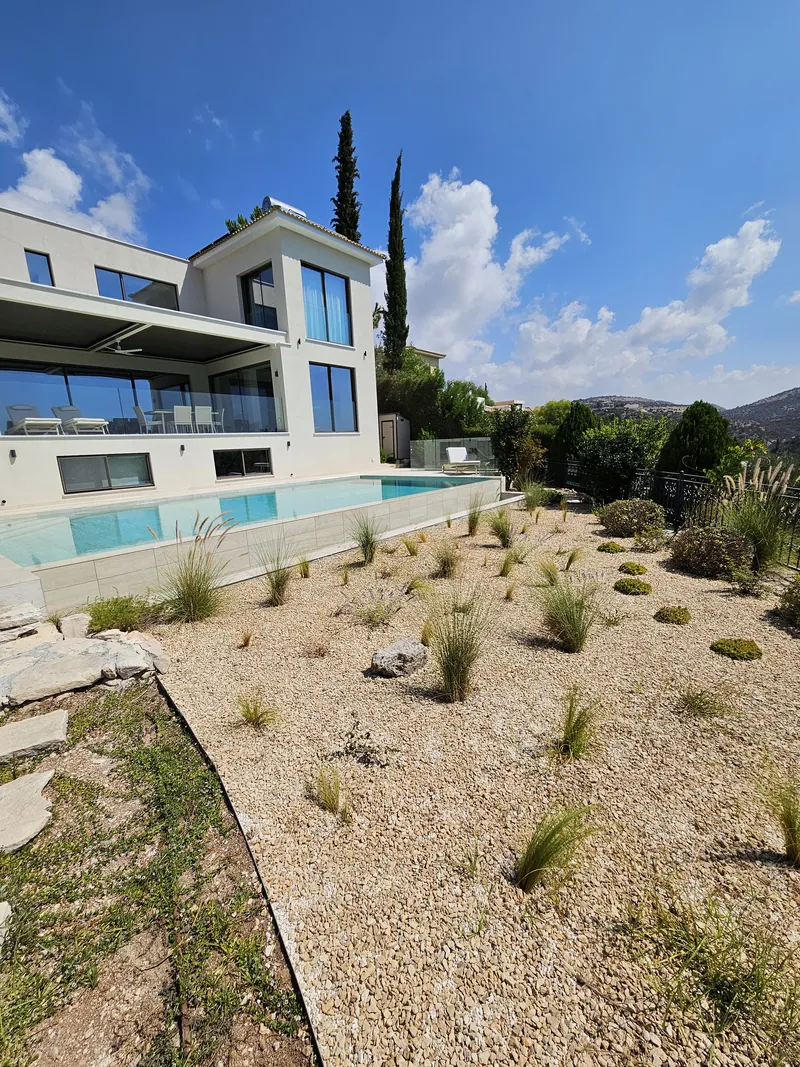 The house and its pool above a gravel slope planted with grasses