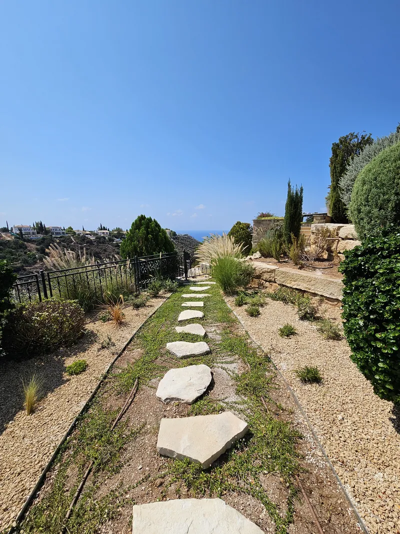 Stepping stones down a gravel slope of grasses, looking out over the valley