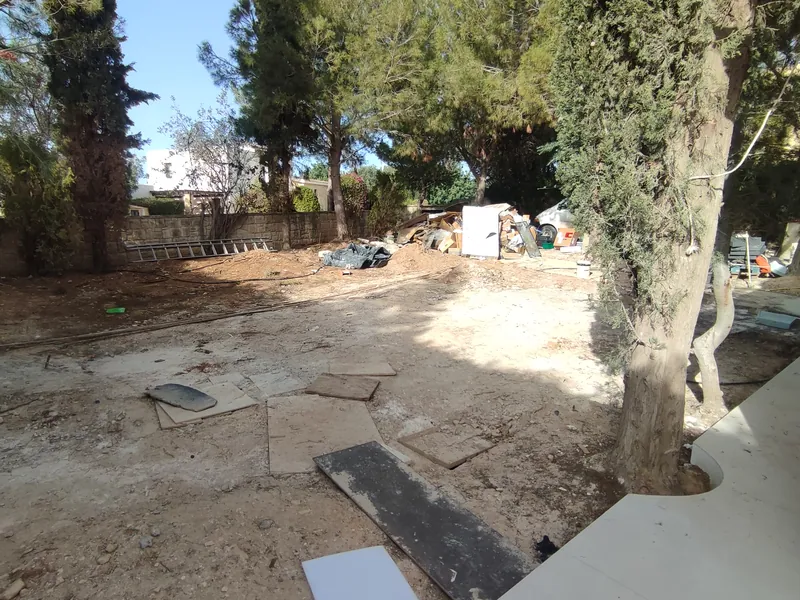 Before: bare earth, rubble and building materials under the pines