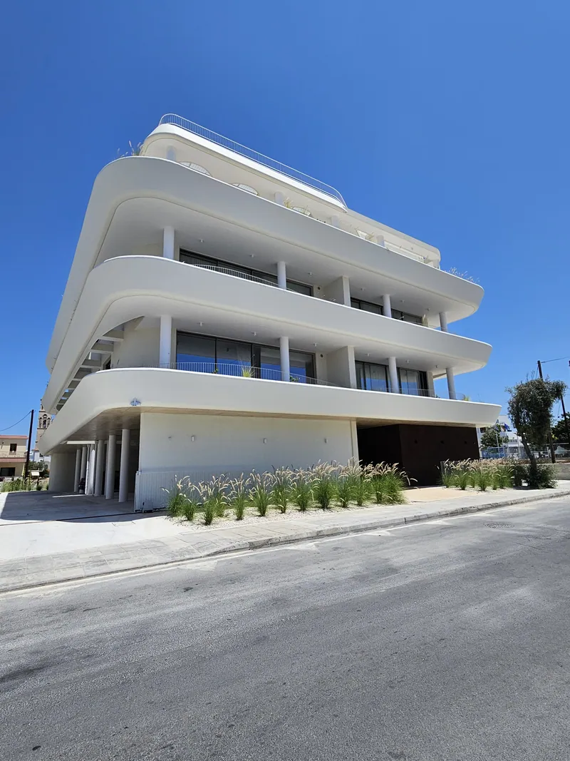 The curved white building with grasses planted along its street front
