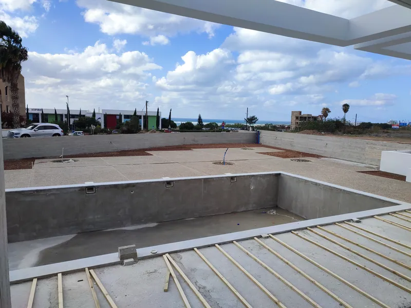 Before: the pool shell and the bare courtyard under construction, the sea in the distance