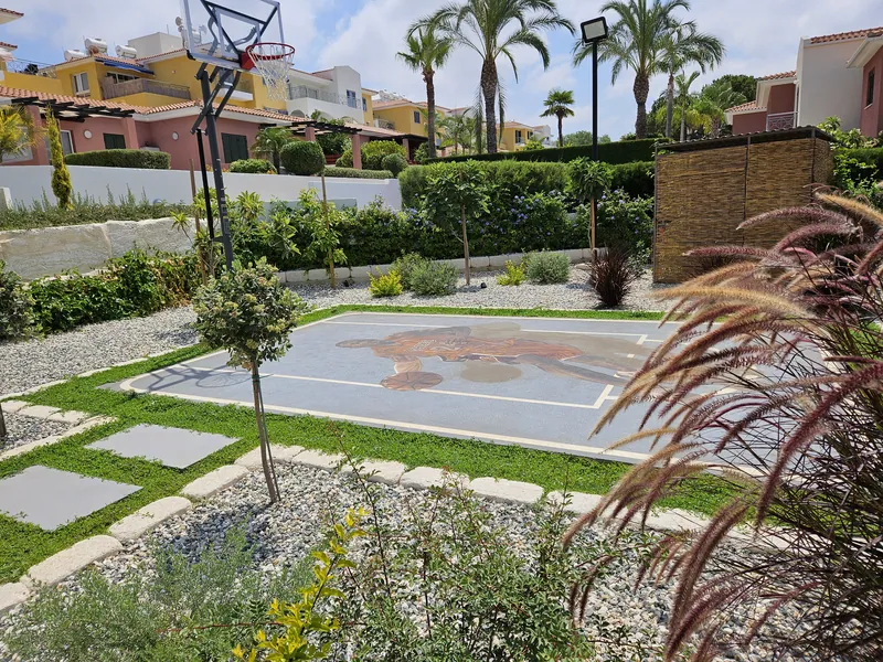A basketball court framed by planted beds, stepping stones and grasses