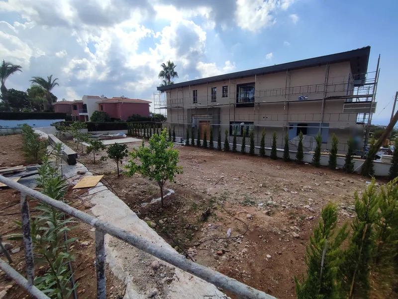 Before: the bare plot beside the house under construction, with young trees just planted