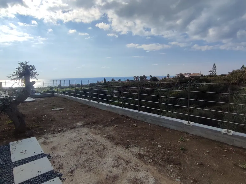 Before: bare earth on the terrace beside the house, an old olive tree and the sea beyond