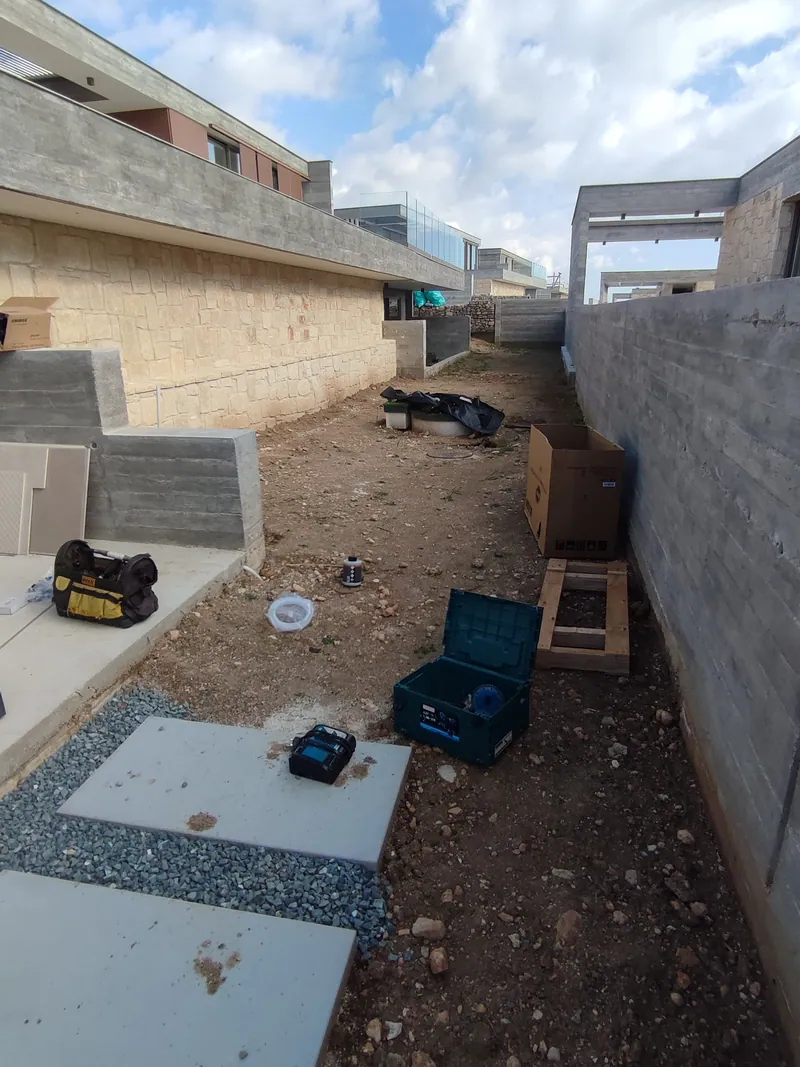 Before: bare earth and paving slabs between the stone-clad house and a concrete wall