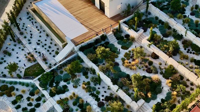 A timber deck above terraces of grasses and shrubs in white gravel