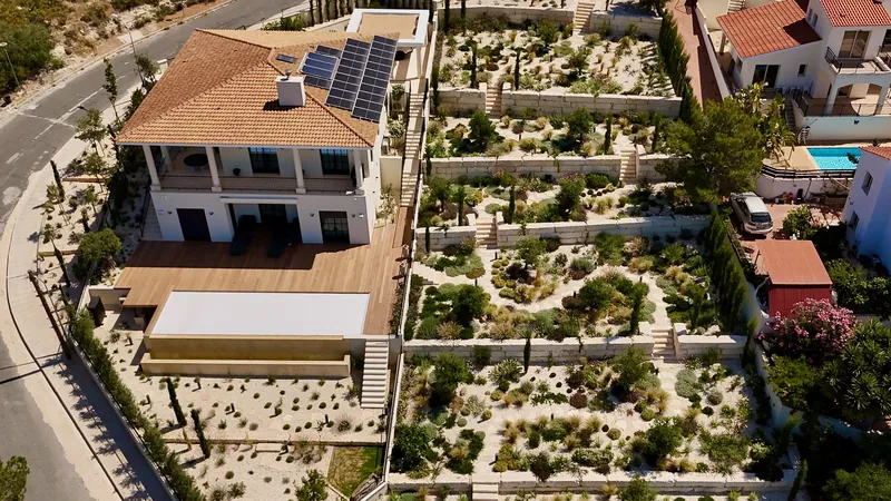 The house and its timber deck above terraced beds of gravel and planting, seen from above