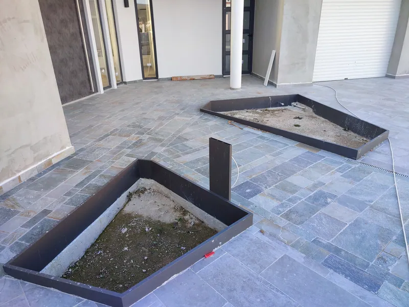 Before: empty steel planters set into the stone paving